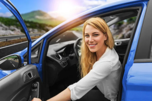 Hermosa chica rubia conduciendo un coche en la carretera. Invitación a viajar. Alquiler de coches o vacaciones . —  Fotos de Stock