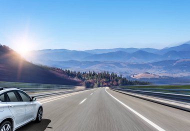 Araba, dağlar ve ormanlar arasında yolda ilerliyor..