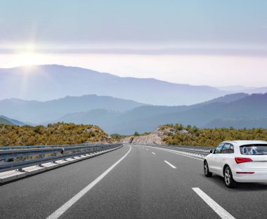 Araba, dağlar ve ormanlar arasında yolda ilerliyor..