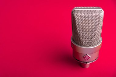 Büyük diyafram yoğunlaştırıcı stüdyo mikrofonu Neumann tm 103 kırmızı arka planda..