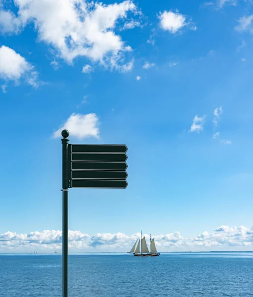 Bir deniz manzarasının arka planında işaretler ve denizde bir yelkenli gemisi.. — Stok fotoğraf