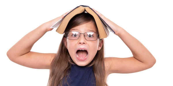 Little girl with an open book on her head is angry. — Stock Photo, Image