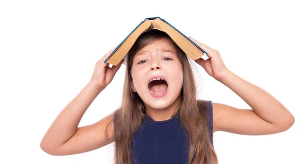 Little girl with an open book on her head is angry. — Stock Photo, Image