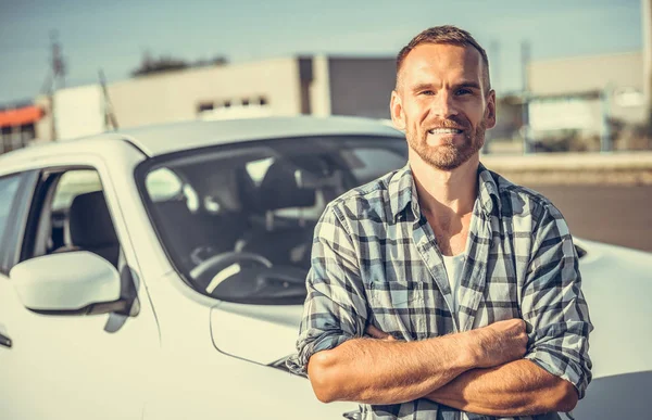 Um jovem atraente fica perto de um carro . — Fotografia de Stock