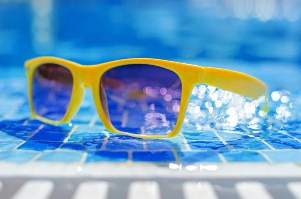 Yellow sunglasses on a background of a pool with water. — 图库照片
