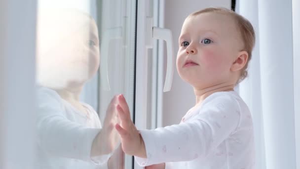 Kind blickt auf die Straße, die am Fenster steht. — Stockvideo