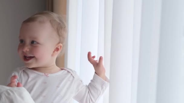 Niña en brazos de su madre cerca de la ventana . — Vídeos de Stock