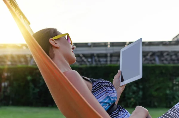 Giovane donna con un computer tablet su un'amaca . — Foto Stock