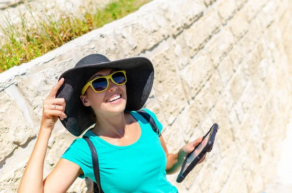 Fashionable young woman tourist in a hat posing on a city street. — Stock Photo, Image