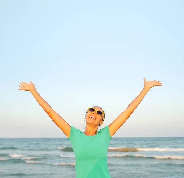 Girl on the beach raises her hands up on the background of the sea. — Stock Photo, Image