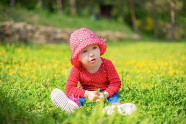 Küçük kız yeşilliğin arka planına karşı doğayla oynuyor..