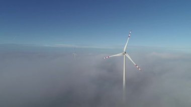 Yerden sisli arka planda dönen rüzgar çarkları boyunca uçan kamera.