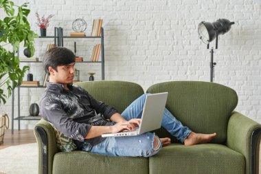 Evden, laptoptan ve müzik tarzından çalışan bir adam.