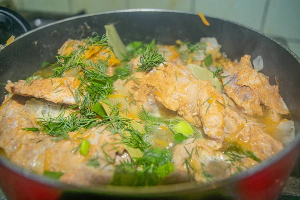 Meat with onions, carrots, dill and Bay leaf is stewed in a saucepan. Home cooking. — Stock Photo, Image