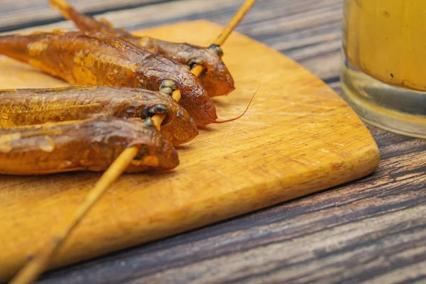 Gedroogde mullet op een houten plank met een mok bier op de tafel. Vis en zeevruchten keuken. Lekker tussendoortje. — Stockfoto