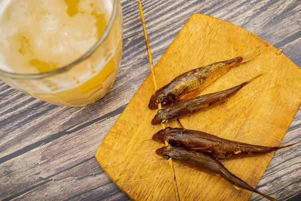 Torkad mulle på en träskiva med en mugg öl på bordet. Fisk och skaldjur mat. Smakligt mellanmål. — Stockfoto