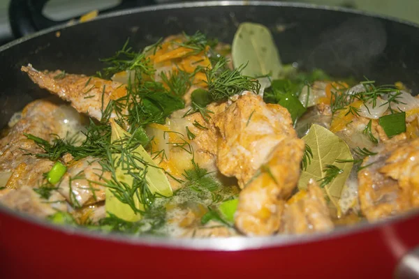 Mięso z cebulą, marchewką, koperkiem i liściem laurowym duszone jest w rondlu. Gotowanie domowe. — Zdjęcie stockowe