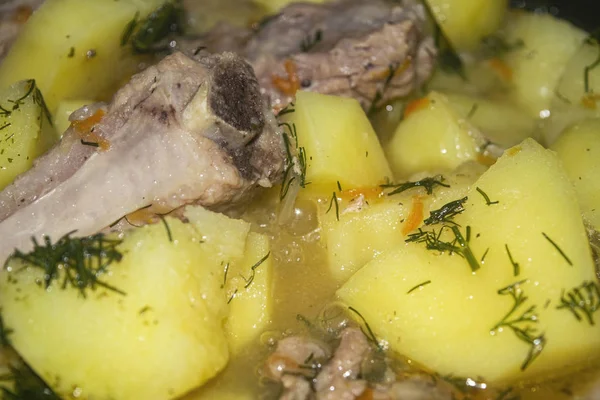 Stewed pork ribs with potatoes, onions, carrots and dill in a saucepan. Close up. Traditional recipe. Home cooking. — Stock Photo, Image