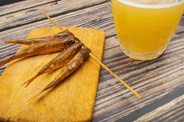 Gedroogde mullet op een houten plank met een mok bier op de tafel. Vis en zeevruchten keuken. Lekker tussendoortje. — Stockfoto