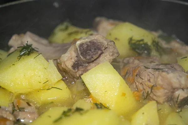 Gedünstete Schweinerippchen mit Kartoffeln, Zwiebeln, Karotten und Dill in einem Topf. Nahaufnahme. traditionelles Rezept. Hausmannskost. — Stockfoto