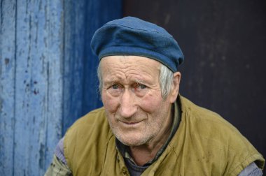 Köy evinin verandasında bereli yaşlı bir adamın portresi..