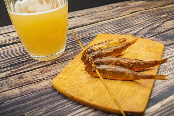 Ahşap bir tahtada, masada bir kupa birayla kurutulmuş kefal balığı. Balık ve deniz ürünleri mutfağı. Lezzetli.. — Stok fotoğraf