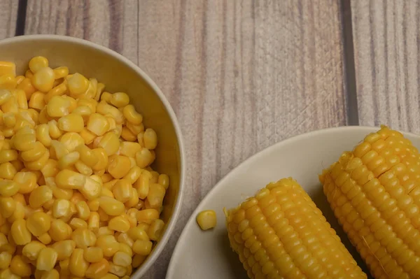 Två öron kokad majs i en tallrik och ett korn majs på bordet. Hälsosam kost. Träningsdiet. För en trevlig njutning. Närbild. — Stockfoto