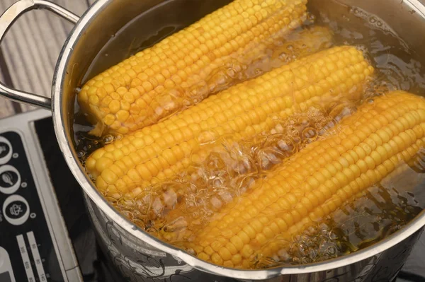 A few ears of corn are cooked in a saucepan. Healthy diet. Fitness diet. For a sweet treat. Close up.