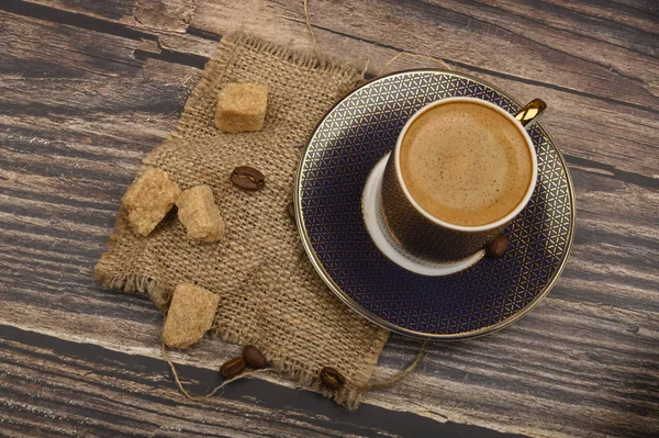 Eine Tasse Kaffee und Stücke braunen Zuckers auf einem hölzernen Hintergrund. — Stockfoto