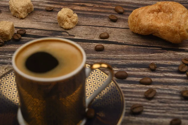 Kaffeetasse, Croissants, brauner Zucker und Kaffeebohnen auf Holzgrund. Nahaufnahme. — Stockfoto