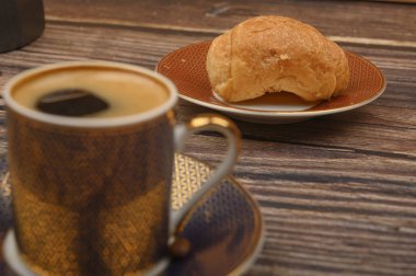 Ahşap arka planda kahve fincanı ve kruvasan. Kapat..