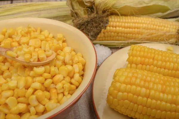 Зерна сладкой кукурузы в тарелке и колосья кукурузы на деревянном столе. Здоровое питание. Фитнес-диета. За сладкое угощение. Закрыть . — стоковое фото