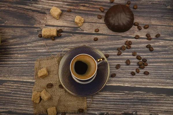 Tasse Kaffee, die Marshmallows in Schokolade, braunem Zucker und Kaffeebohnen auf Holzgrund. Nahaufnahme. — Stockfoto