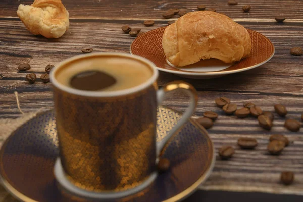 Kaffeetasse, Croissants und Kaffeebohnen auf Holzgrund. Nahaufnahme. — Stockfoto