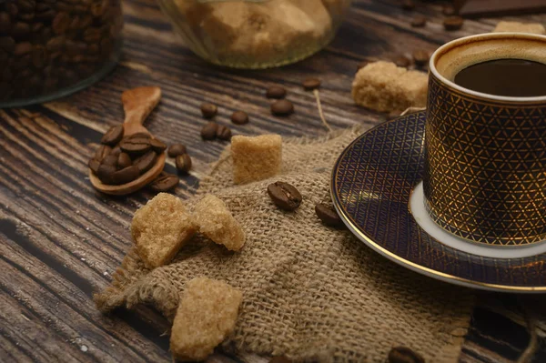 Kaffeetasse, Kaffeebohnen, brauner Zucker auf Holzgrund. Nahaufnahme. — Stockfoto