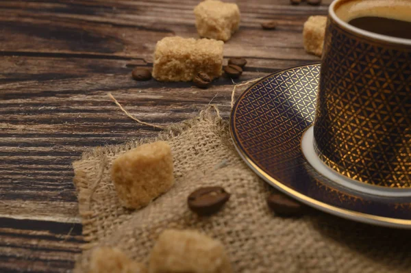 Kaffeetasse, braunem Zucker und Kaffeebohnen auf Holzgrund. Nahaufnahme. — Stockfoto