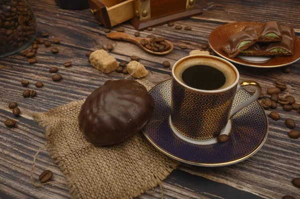 Eine Tasse Kaffee, Marshmallows in Schokolade, Kaffeebohnen, brauner Zucker auf einem Holzuntergrund. Nahaufnahme. — Stockfoto