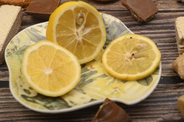 Bir tabakta dilimlenmiş limon ve ahşap bir arka planda. Kapat..