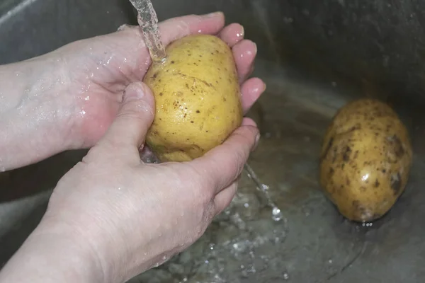 Чоловічі руки миють під проточною водою нечисту картоплю. Домашня кухня. крупним планом — стокове фото