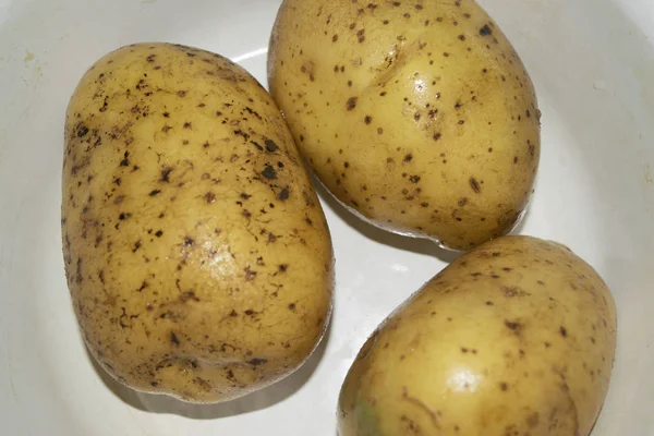 Trois pommes de terre lavées non pelées dans une assiette blanche. Cuisine maison. Gros plan — Photo