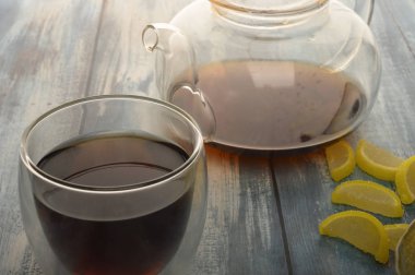 Marmelat limon dilimleri, bir bardak siyah çay ve ahşap zemin üzerinde demlenmiş çay. Tatlı tatlı. Kapat..