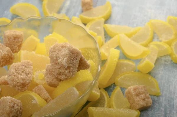 Marmalade lemon slices and pieces of brown sugar on a wooden background. Sweet dessert. Close up. — Stock Photo, Image