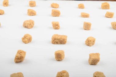 Beyaz arkaplanda esmer şeker parçaları.