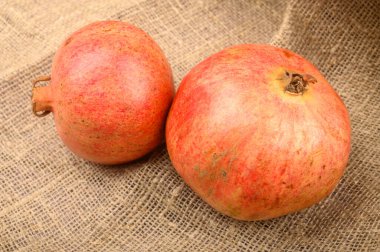 Yakın plan kabataslak ev yapımı kumaşların arka planında iki olgun nar. Fitness diyeti. Sağlıklı beslenme.