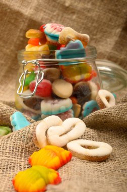 Kaba ev yapımı kumaşın arka planında cam bir kavanozda çok renkli marmelat. Lezzetli tatil hediyesi..