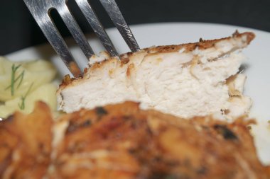 Baharatlı tavuk göğsü, otlu haşlanmış makarna, beyaz bir tabakta kesilmiş bir parça göğsü olan metal çatal..