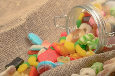 Kaba ev yapımı kumaşın arka planında cam bir kavanozda çok renkli marmelat. Lezzetli tatil hediyesi..