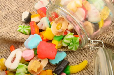 Kaba ev yapımı kumaşın arka planında cam bir kavanozda çok renkli marmelat. Lezzetli tatil hediyesi..