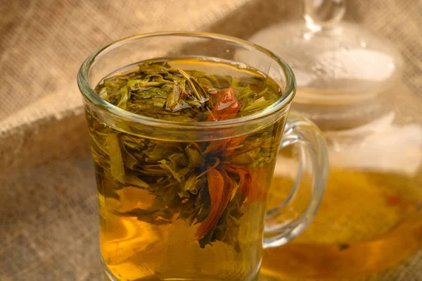 Flower tea brewed in a glass Cup, a glass teapot with flower tea on a background of rough homespun fabric. Close up. — 스톡 사진