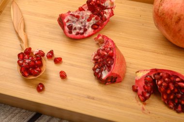 Olgun sulu nar, nar dilimleri ve tahta bir arka planda tahta bir tepside tahta bir kaşıkta nar tohumları. Kapat..